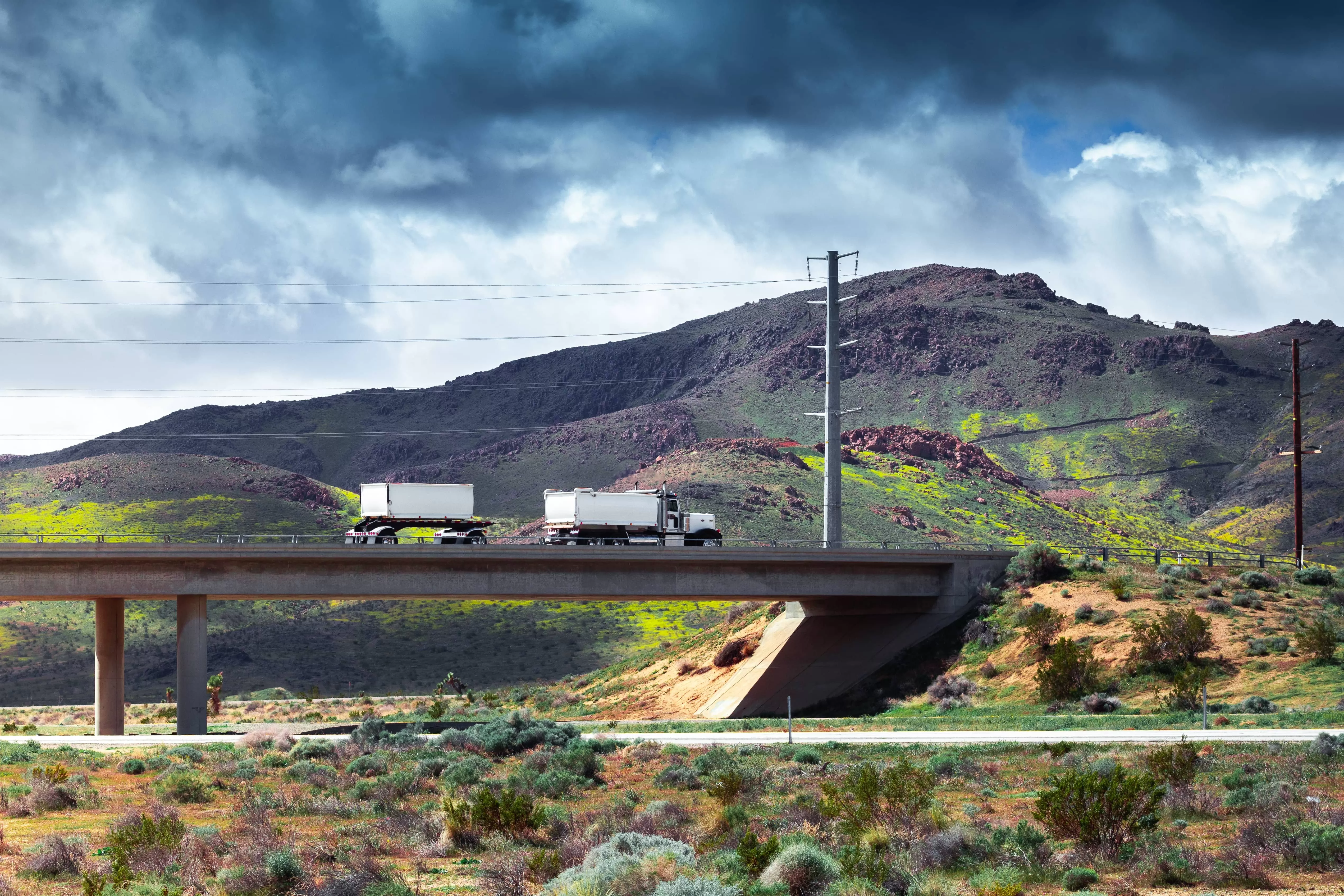 White truck with two trailers on the bridge