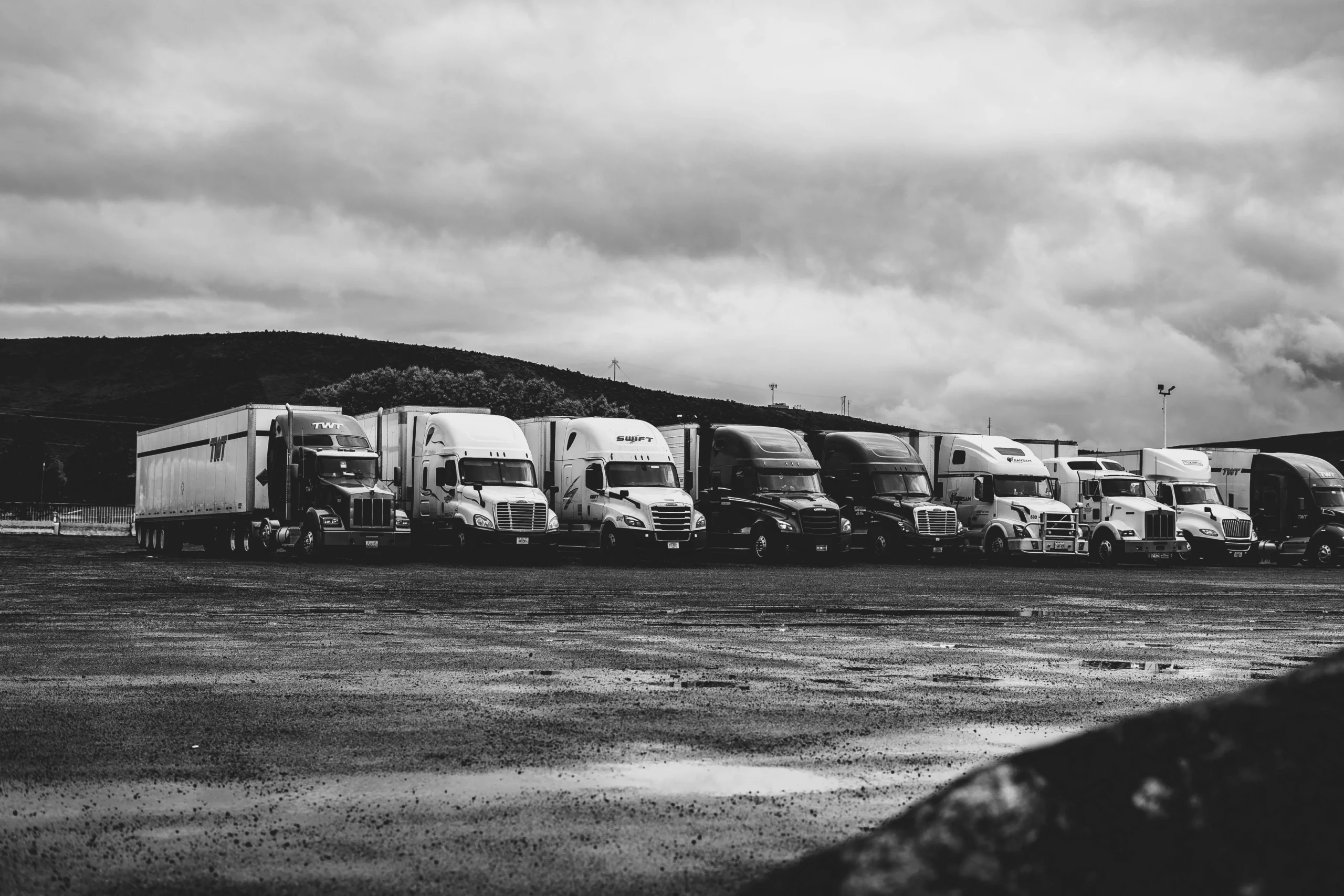 photo of trucks on the road in grayscale scaled